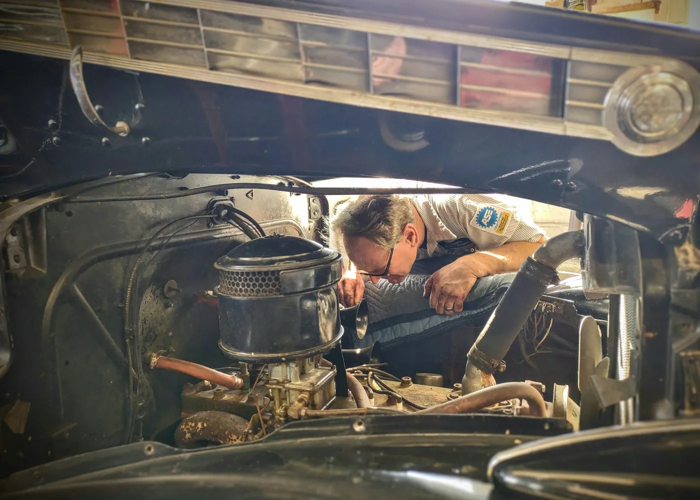 Propietario revisando el motor de un coche veterano en un garaje
